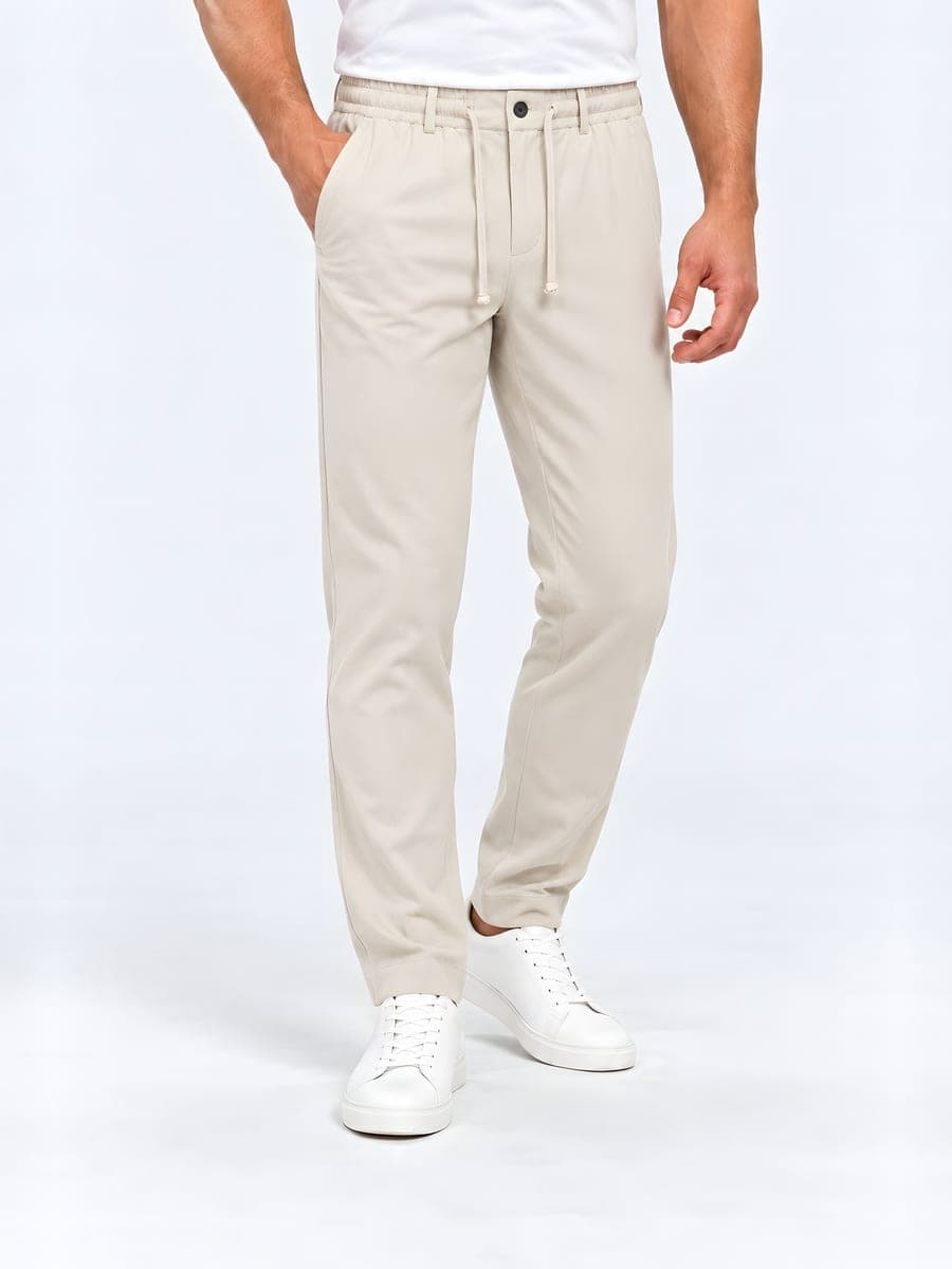 Beige tapered broek met trekkoord, gedragen met een hand in de zak