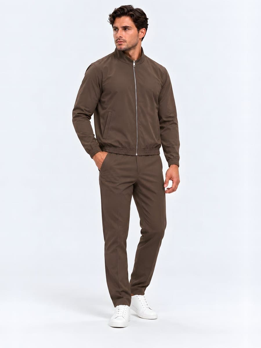 Bruine technische set: jack en broek, gedragen met een hand in de zak