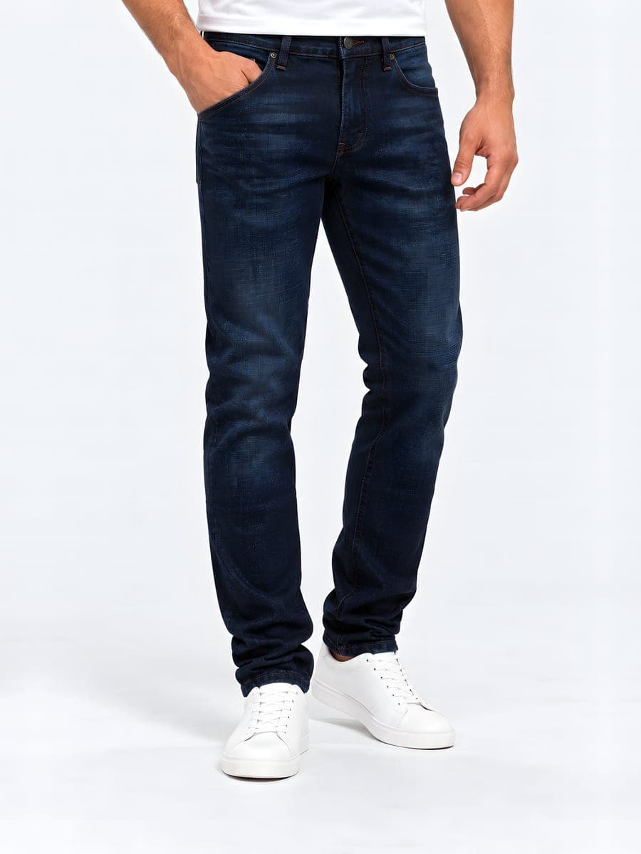 Slim fit jeans in dark blue, worn with a hand in the pocket