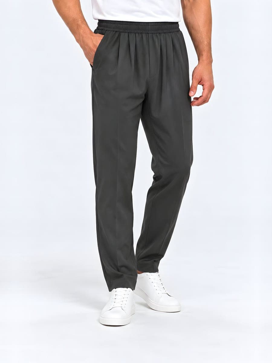 Straight leg trousers with an elastic waist in dark grey, worn with a hand in the pocket