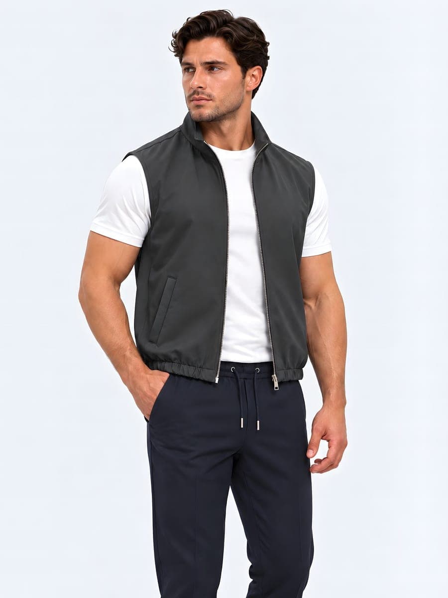 Grijze polyester bodywarmer met tweewegrits, gedragen met een hand in de zak