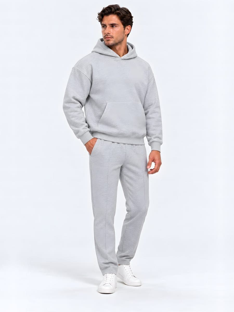 Lichtgrijze oversized hoodie-set, gedragen met een hand in de zak