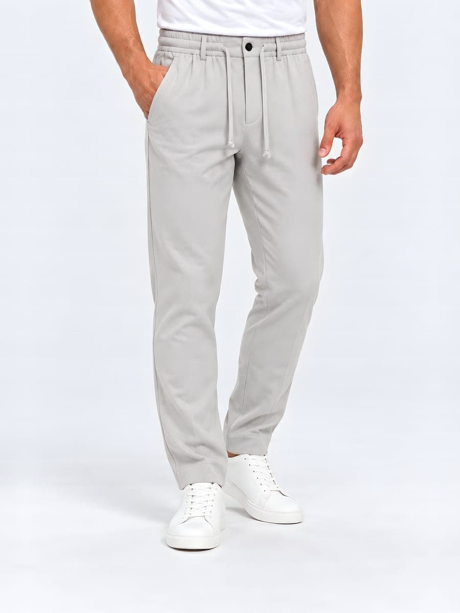 Tapered drawstring trousers in light grey, worn with a hand in the pocket
