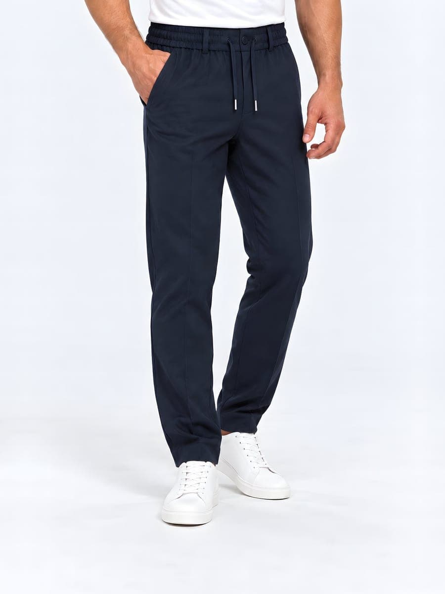 Navy tapered broek met trekkoord, gedragen met een hand in de zak