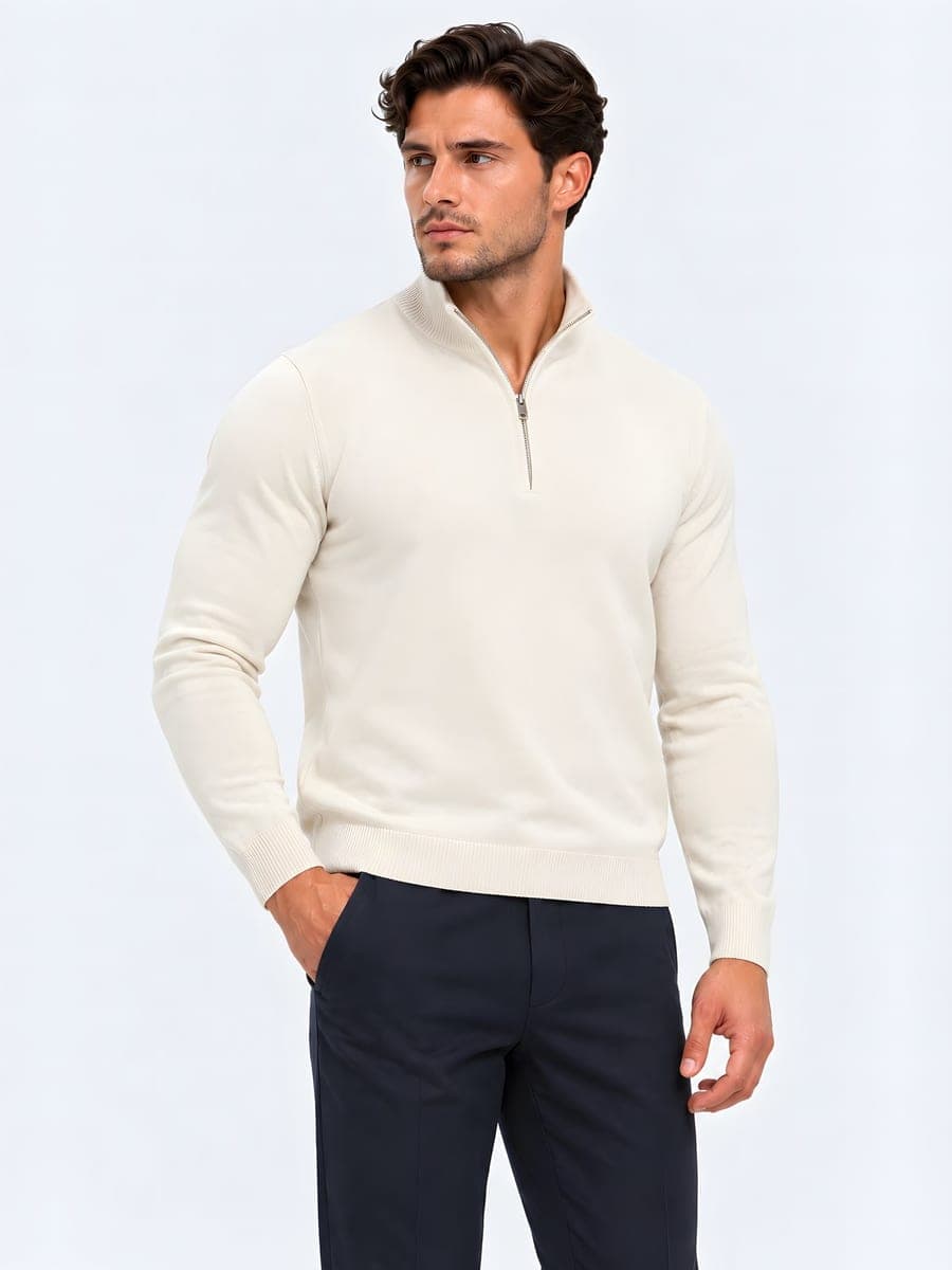 Zandkleurige aansluitende knit met korte rits, gedragen met een hand in de zak