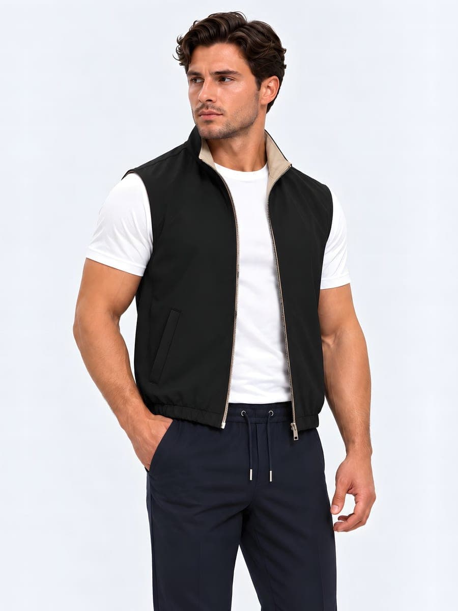Zwart-beige omkeerbare bodywarmer, gedragen met een hand in de zak