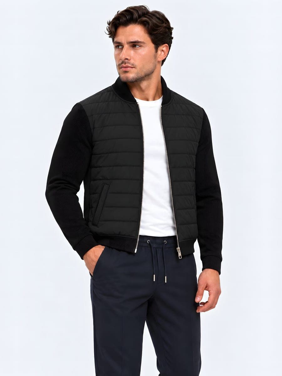 Jacket with a quilted body and plain sleeves in black, worn with a hand in the pocket