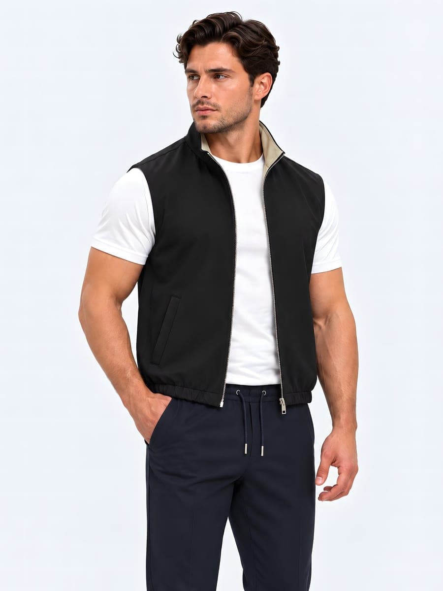 Zwart-zand omkeerbare bodywarmer met metalen rits, gedragen met een hand in de zak