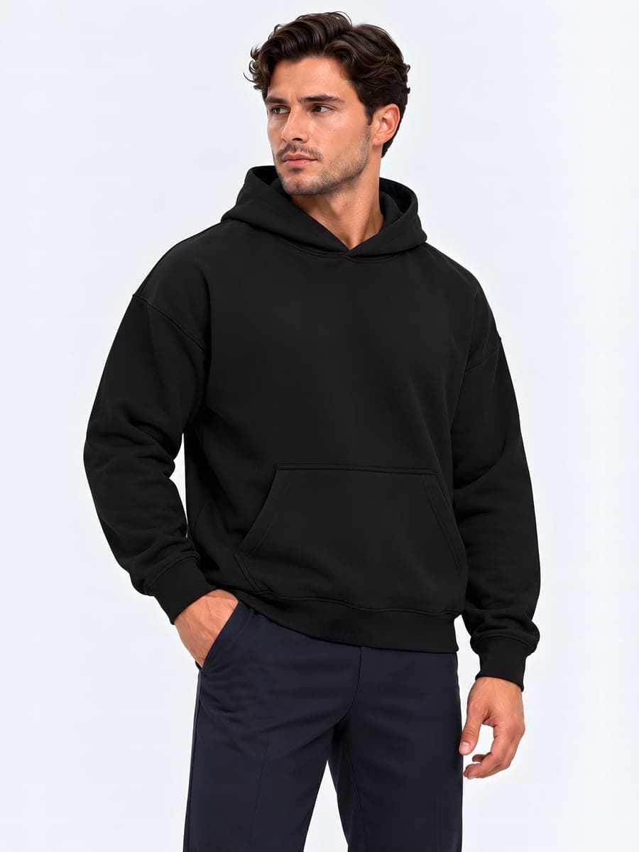 Zwarte oversized hoodie, heavyweight, gedragen met een hand in de zak