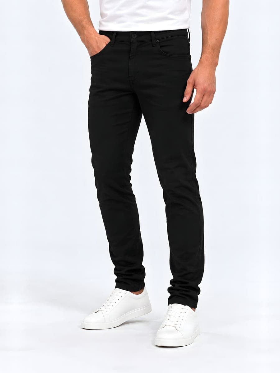 Zwarte slim fit jeans, gedragen met een hand in de zak
