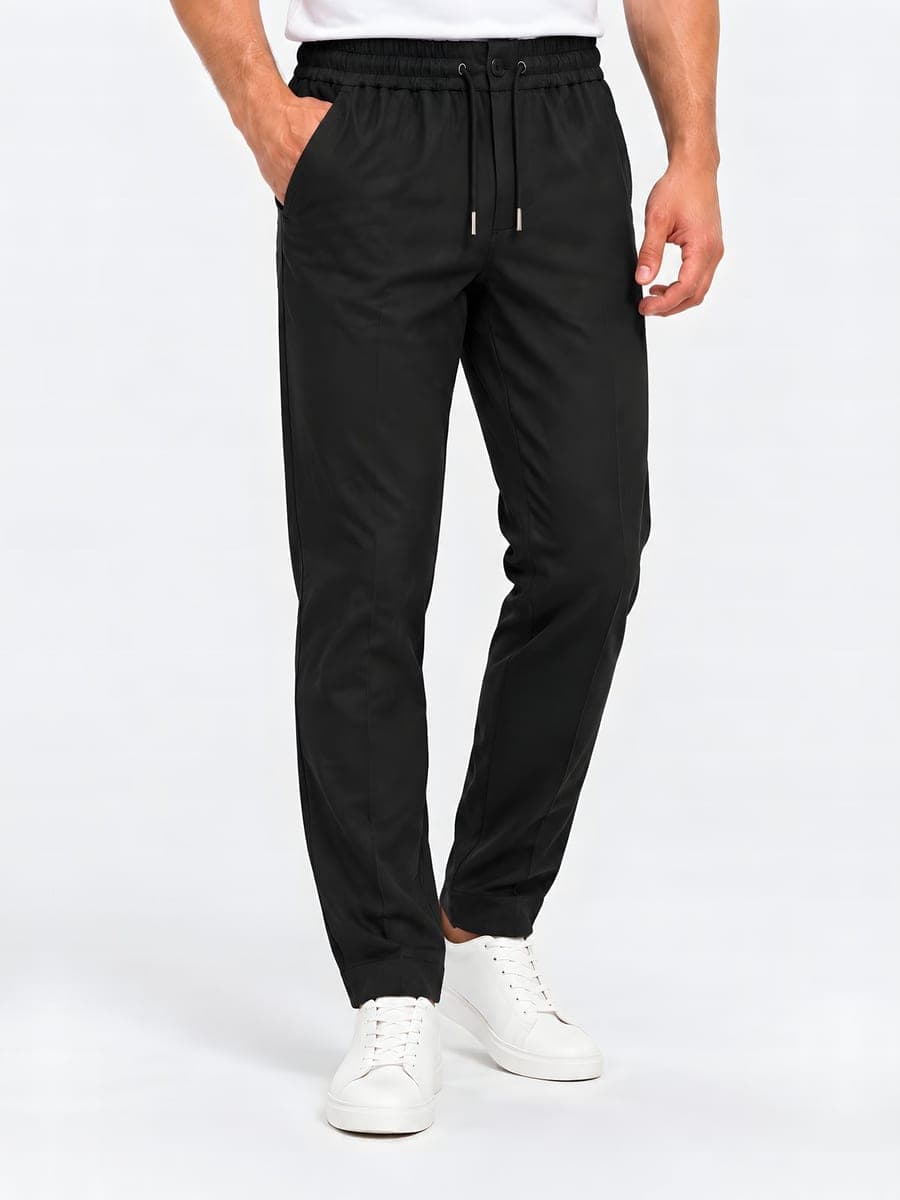 Tapered drawstring trousers in black, worn with a hand in the pocket