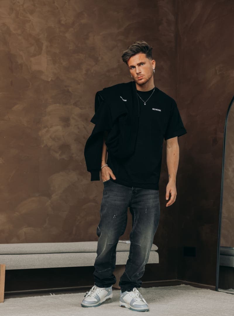 Model in a black t-shirt with a hoodie over the shoulder