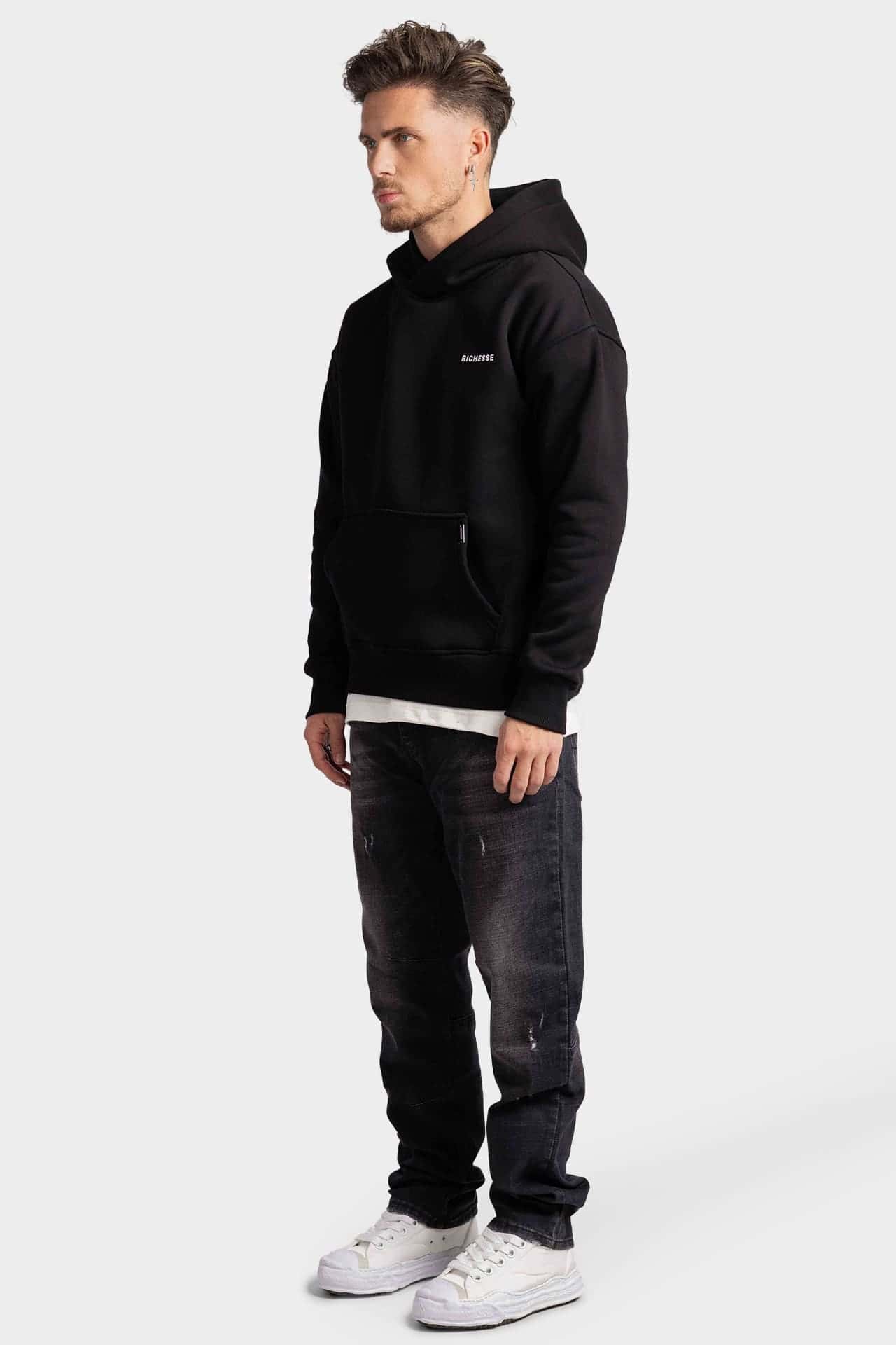 Black hoodie in side view with a small chest logo and a label on the kangaroo pocket