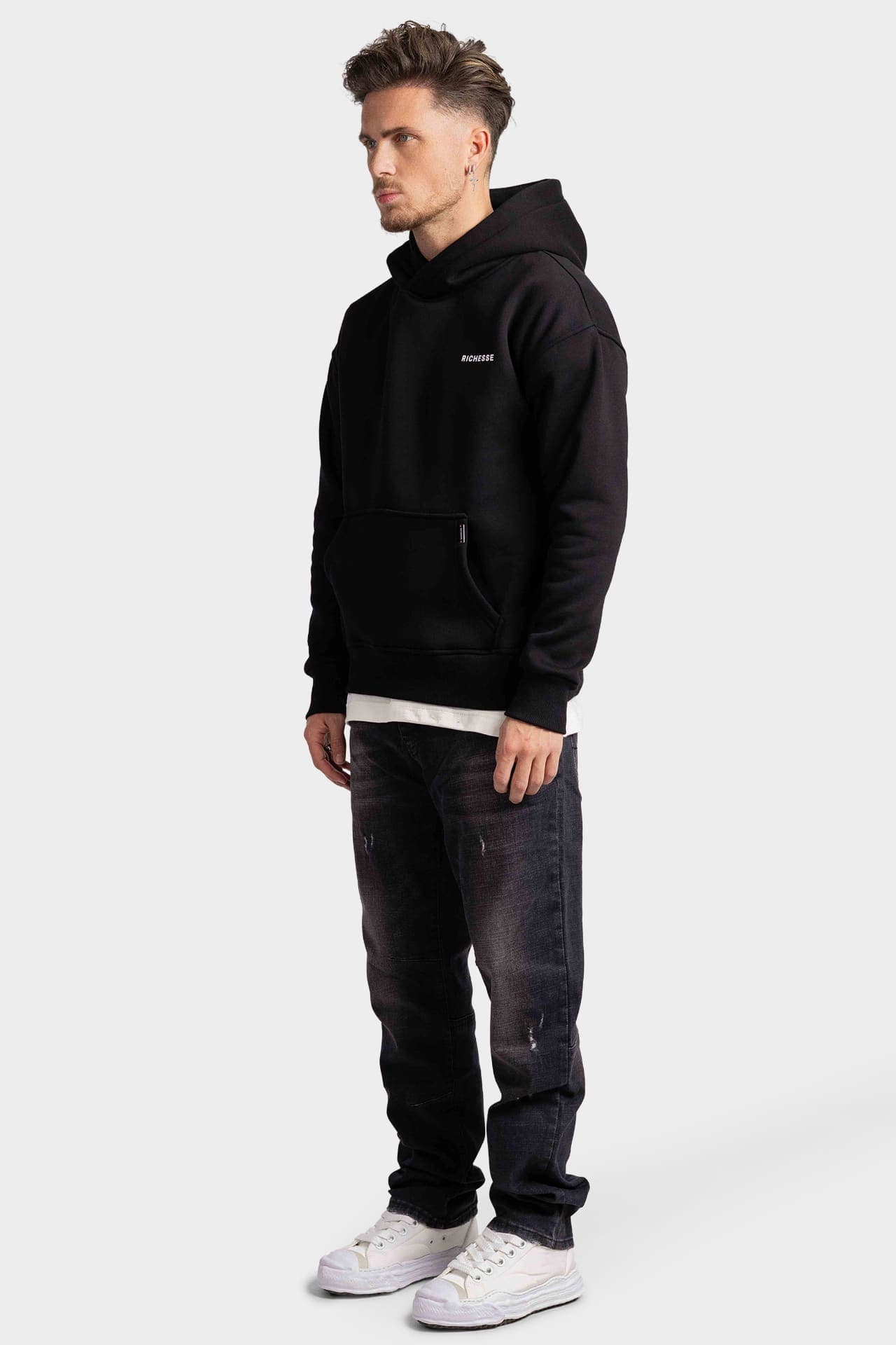Zwarte hoodie in zijaanzicht met borstlogo